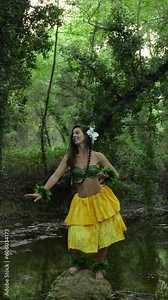 Hula dancer performing art and culture of hawaii in the middle of the forest connecting with nature in a personal wellness ritual.