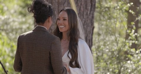 Ceremony of two diverse women. First kiss In a peaceful outdoor setting, multiethnic lesbian couple joyfully embraces in elegant wedding attire, celebrating their love, LGBT wedding