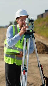 Surveyor engineer using theodolite measuring construction site