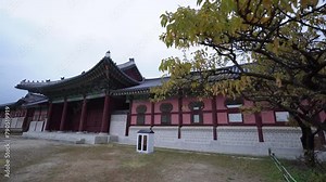 a traditional Korean building at Gyeongbokgung, Seoul, featuring intricate designs, vibrant colors, under a cloudy sky with a mountain in the background