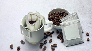 Drip coffee bag with ground coffee in  cup