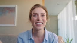 beautiful young woman having video chat using webcam at home waving...