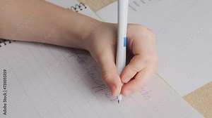 left-handed schoolchild doing homework, child writes English in notebook, assignments involving English language exercises, acquisition, vocabulary building in school setting, Bilingual Education