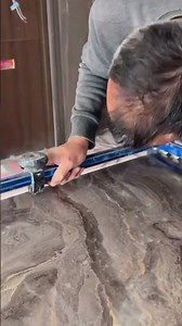 cutting a large dark marble tile precisely using a blue manual tile cutter tool for construction