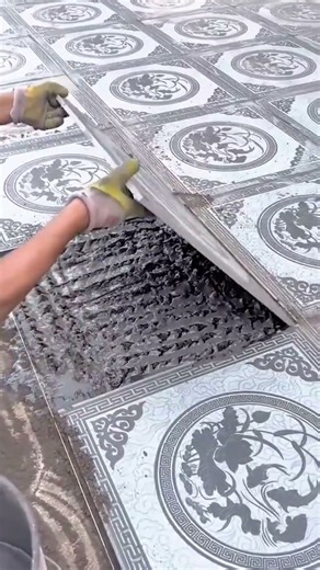 Skilled worker meticulously lifts a patterned tile revealing the fresh wet adhesive beneath it