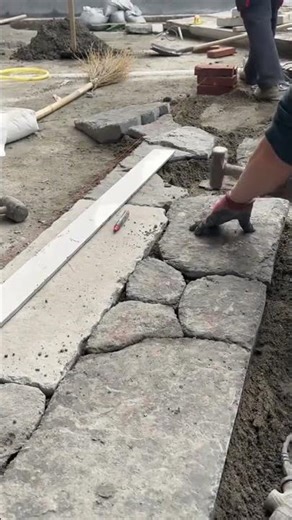 Worker Using Rubber Mallet To Install Natural Stone Pavers