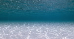 Blue sea underwater with sandy sea bottom and waves. Ocean background