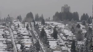 Heavy snowfall over the Burnaby Heights neighborhood with the clouded skyline of Vancouver in the far distance as seen from Capitol Hill in Burnaby, British Columbia, Canada