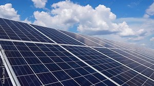 Blue cells of solar panels installed in a row at a solar power plant. Blue sky with thick clouds. Top View of Solar Power Station.