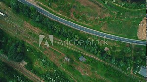 Bird-eye view on countryside landscape with highway traffic and railway tracks on the side.