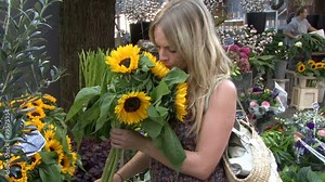 Female buying flowers on flower market and smelling them