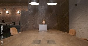 Woman using laptop sitting to wooden table with chairs, device on a table, young student using technology in open space office room. Concept of coworking