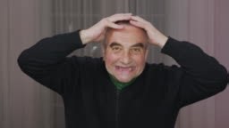 Senior man scares rubbing his head , opening his toothless mouth...