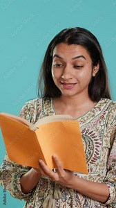 Vertical video Radiant person reading interesting book, enjoying hobby, being entertained, isolated over studio background. Upbeat woman with novel in arms enjoying relaxation time, reading text aloud