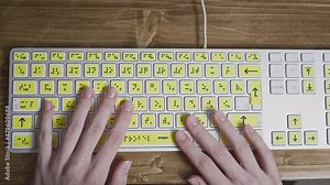 Close-up of a computer keyboard with braille. A blind girl is typing words on the buttons with her hands. Technological device for visually impaired people. Tactilely touches bumps on the keys
