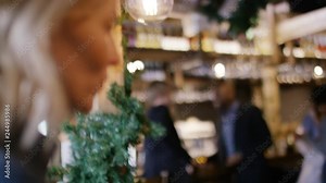 Two men standing at a bar watch two women sitting at a table in conversation