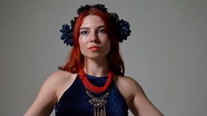 Portrait of confident belly dancer performing in slow motion at grey background. Young slim Caucasian woman dancing Middle Eastern dance with serious facial expression