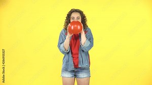 The girl inflates a red balloon, takes in hand and releases, the ball is blown away and flies away