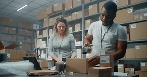 Multiethnic Delivery Service Workers Packing Cardboard Parcels with Online Goods, Food, Scanning Code with Scanner, Preparing Packages for Shipping to Clients. Retail Warehouse of E-Commerce Store.