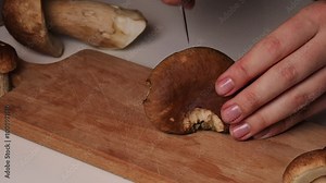 Female chef’s hands are slicing a boletus mushroom into pieces. The process of making a porcini mushroom recipe