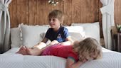 Cute sweet toddler children, tickling feet on the bed, laughing and...