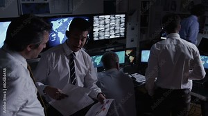 Time lapse of security team watching the screens in a dark system control room