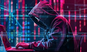 Hacker with hood working on a laptop with a binary code background.