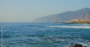 Remote controlled unrecognizible drone flies over water. High resolution video camera flying above the sea against a sunset sky.