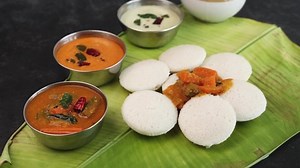Rotation shot of many Idli or idly on banana leaf. Popular South Indian breakfast vegetarian food restaurant in Kerala Tamil Nadu India Sri Lanka. healthy steamed rice cakes .