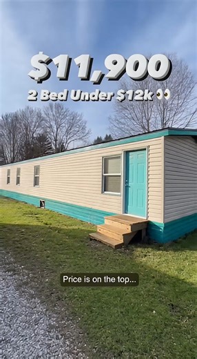 used 2-bedroom mobile home priced at $11,900. From the outside, it looks simple and older, but it sits level and stable. Inside, the living area provides enough open space for basic furniture and daily living. The kitchen is dated but fully functional with working plumbing. The first bedroom fits a full-size bed comfortably, while the second bedroom works well as a smaller bedroom or office space. The bathroom functions properly with only a minor drawer issue. For under $12k, this offers two bed