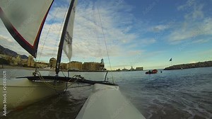Windsurfing catamaran pulled ashore, coast city and bay creating skyline at back