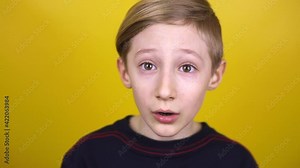 The child opens his mouth wide and yawns. The boy demonstrates various emotions on a yellow background.