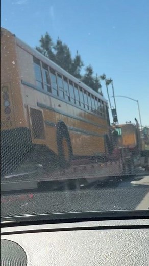 A school bus on the road being carried by a big tow truck