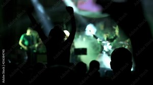Shot of some cheering fans at a life concert, slow motion. girl at a concert seating on shoulders and raising her hands.