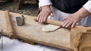 Rolling out dough with a wooden splinter for making pasta, bread, pizza. Close-up of senior women's hands. Ancient authentic and cultural heritage