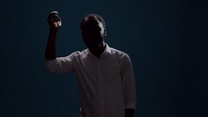 Young man sitting in the dark and holding flashlight to see, using lantern to search and do serious investigation. Active confident person with light looking around to find evidence. Night adventure