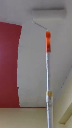 Person Using Long Roller To Apply White Paint On Ceiling