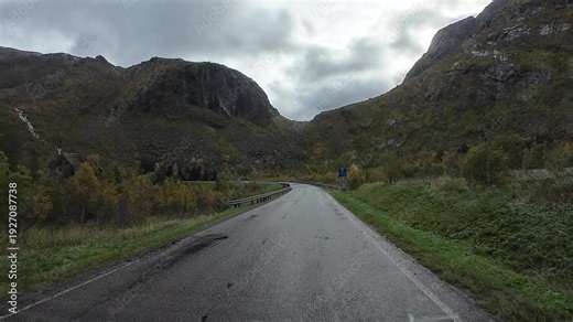 Scenic road trip through a mountain valley on the island of Senja, Norway, ending at a tunnel