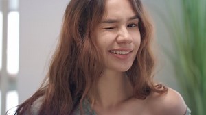 Portrait attractive woman winking eye and smiling into camera. Close up face playful young woman winking eye. Flirt, seduction, temptation concept. Positive people emotions