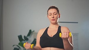 Fitness workout training. Woman picking up dumbbells. Plus size female doing sports exercise at home indoor. Girl in sportswear have workout weight training for weight loss. Sport and fitness