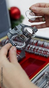 Doctor selecting lenses to the trial frame. Hands of female optometrist picking up test lenses from case for eyesight examination Close-up. Vertical video