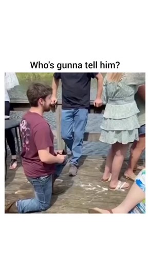 I am facts on Instagram: "The post shares a 27-second video clip of a man proposing marriage on a lakeside dock surrounded by friends and family, where the woman's unenthusiastic response-looking away and minimal engagement-creates palpable awkwardness, overlaid with a meme reaction questioning if someone should inform him of her disinterest. - Posted by meme account @alphafox on 3 January 2026, it amassed over 10 million views in two days, tapping into viral trends of public proposal fails that
