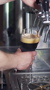Barman pours dark beer into a glass from the beer tap in the pub. Bartender pouring perfect beer for client. Vertical video.