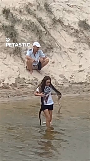 Girl carries large snake across creek in fearless wildlife moment