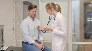 Female Doctor Listening To Patient Chest Using Stethoscope