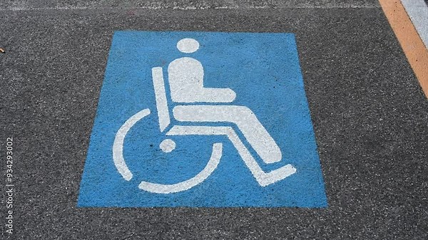 Parking space sign reserved for person with disability on the street. Wheelchair symbol on asphalt.