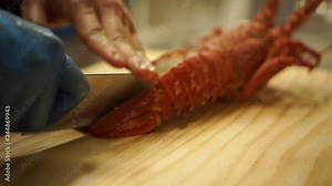 Close Up - Cutting down through a cooked New Zealand crayfish to split it in halves on a wooden cutting board