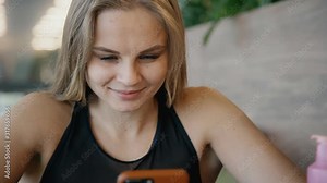 hipster young woman using smart phone to surf internet in gym cafe after workout. smiling female chats. concept of modern world, technology, waiting, business. Stock Video