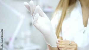 Female doctor or nurse puts a glove on his hand, close-up.