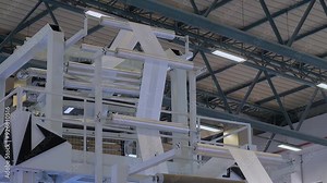 Winding system of blown plastic film extrusion machine with polypropylene film after extrusion at exhibition, trade show: making plastic film. Manufacturing, recycling, industry and equipment concept